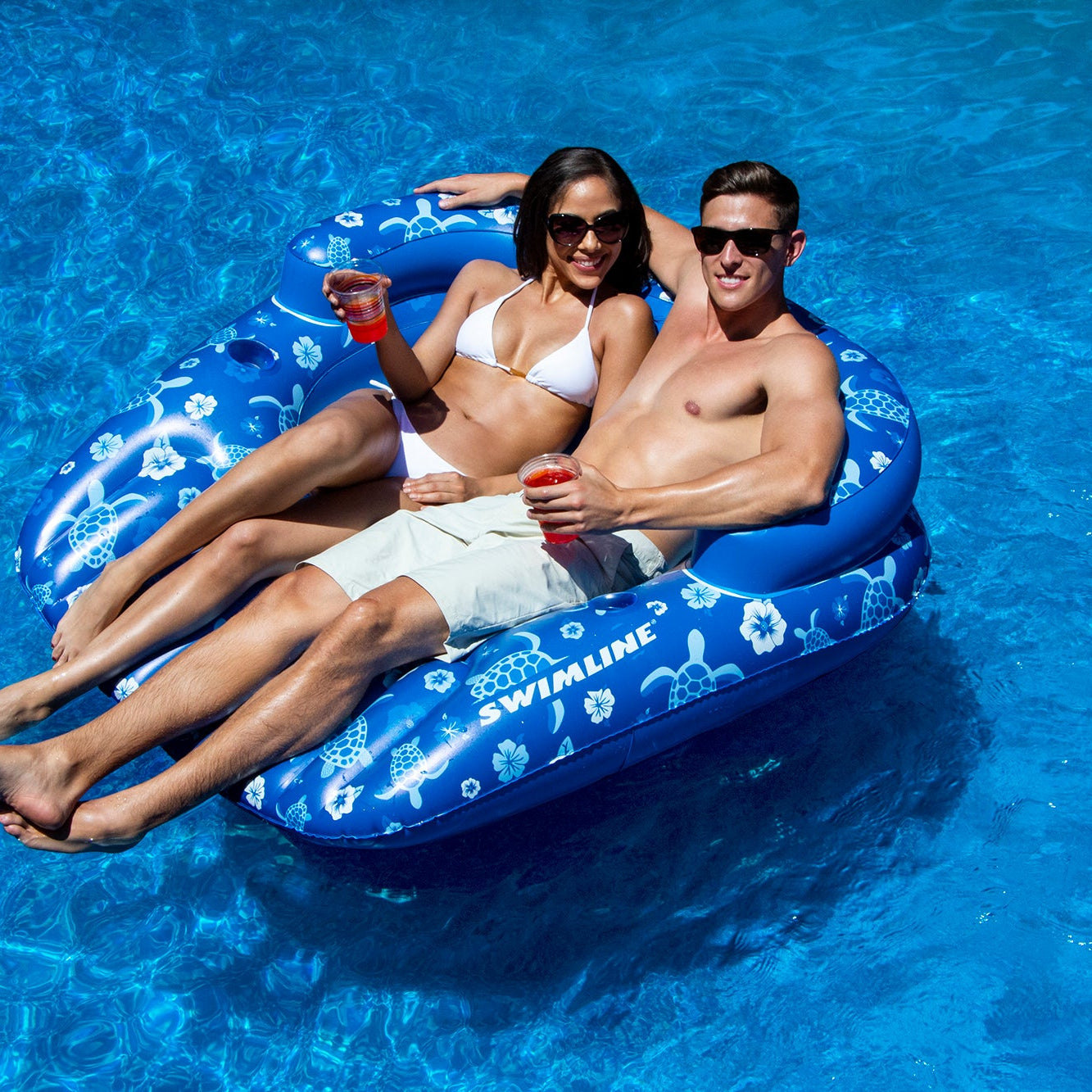 Two people relaxing on a blue inflatable tube in a pool.