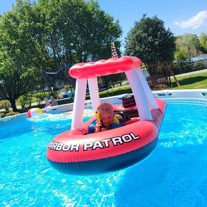 Child riding Swimline Fire Boat Super Squirter inflatable in pool