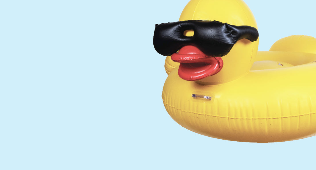 Yellow duck float with black sunglasses on a light blue background