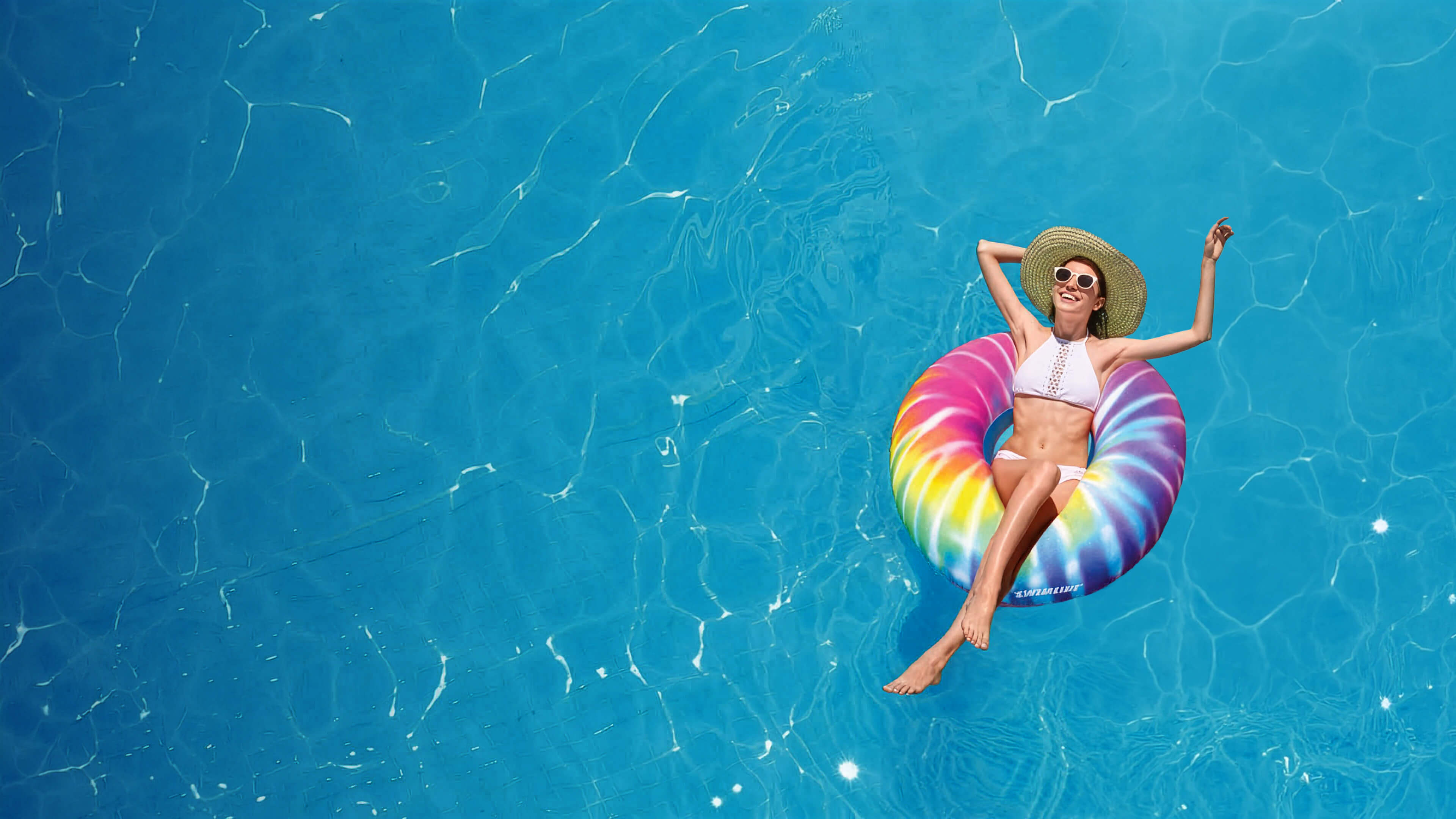 Woman on a colorful tie-dye inflatable ring in a pool